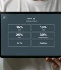 a server with an ipad showing tipping percentages to a customer