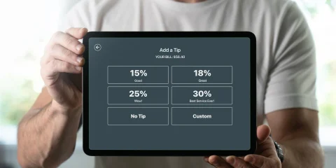 a server with an ipad showing tipping percentages to a customer