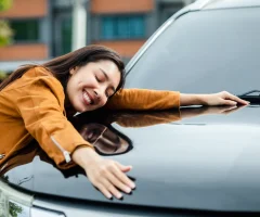 Happy woman hugging her car, showing affection and excitement.