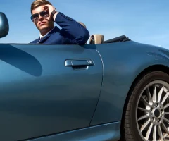 A person driving a stylish convertible car on a scenic road in Mexico