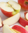 An apple cut into pieces on a wooden surface