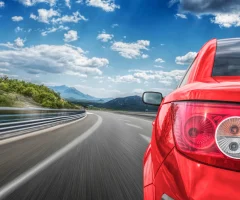 A vibrant red car driving along a scenic road in Mexico