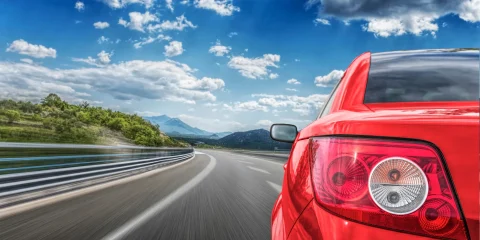 A vibrant red car driving along a scenic road in Mexico