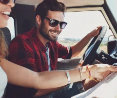 A couple sitting inside their car, looking at a map while planning their trip