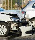 A wrecked car on the side of the road, with visible damage to the front