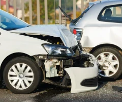 A wrecked car on the side of the road, with visible damage to the front