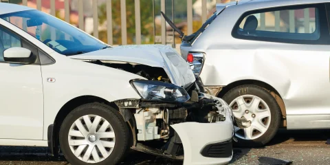 A wrecked car on the side of the road, with visible damage to the front