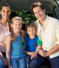 A happy family of four sitting in the trunk of a van