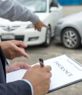 A man signing an insurance document with a pen