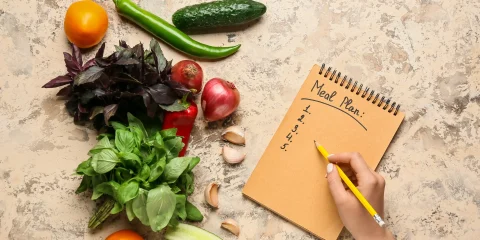 A to-do list placed next to a variety of fresh vegetables on a countertop