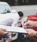 A person signing a document handed to them by another person