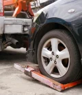 A close-up of a car's tire being lifted by a tow truck, showing the process of it being towed away.