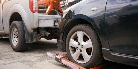 A close-up of a car's tire being lifted by a tow truck, showing the process of it being towed away.