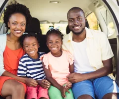 A family of four happily preparing for a road trip to Mexico