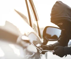 A person attempting to break into a car, showcasing the importance of vehicle security.