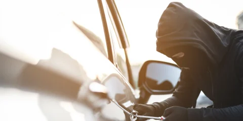 A person attempting to break into a car, showcasing the importance of vehicle security.