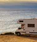 An RV parked in front of the sea, offering a stunning view of the ocean and a peaceful getaway.