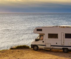 An RV parked in front of the sea, offering a stunning view of the ocean and a peaceful getaway.