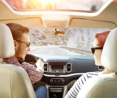 Two people inside their car having a conversation while on a road trip.