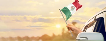 Car driving with a Mexican flag waving from the co-pilot window