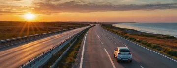 Car driving down a scenic road at sunset