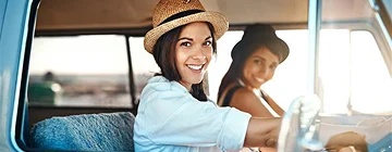 2 friends turning towards the camera while inside of their car